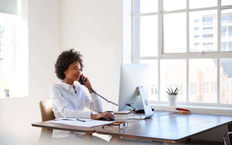 Modern workplace with woman using business phone